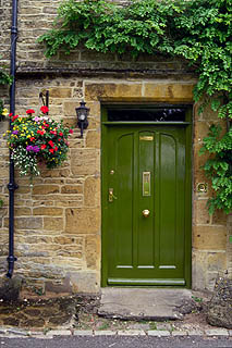 蜂蜜色の壁と緑のドアと花かご